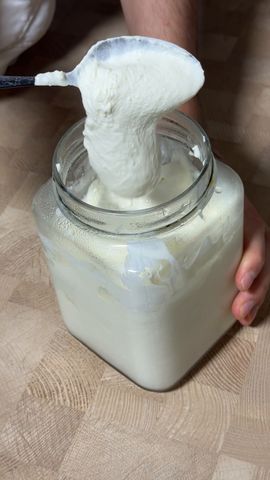 Ложка поднимает густые сквашенные сливки