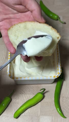 Ложка плавленого сыра над хлебом
